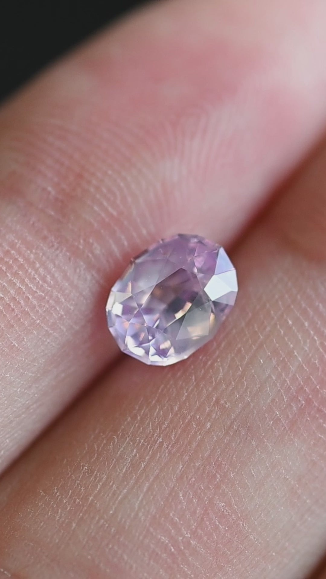 Rotating loose opalescent pink peach sapphire from Ratnapura showing shifting blush and soft apricot tones across the precision oval mix cut.