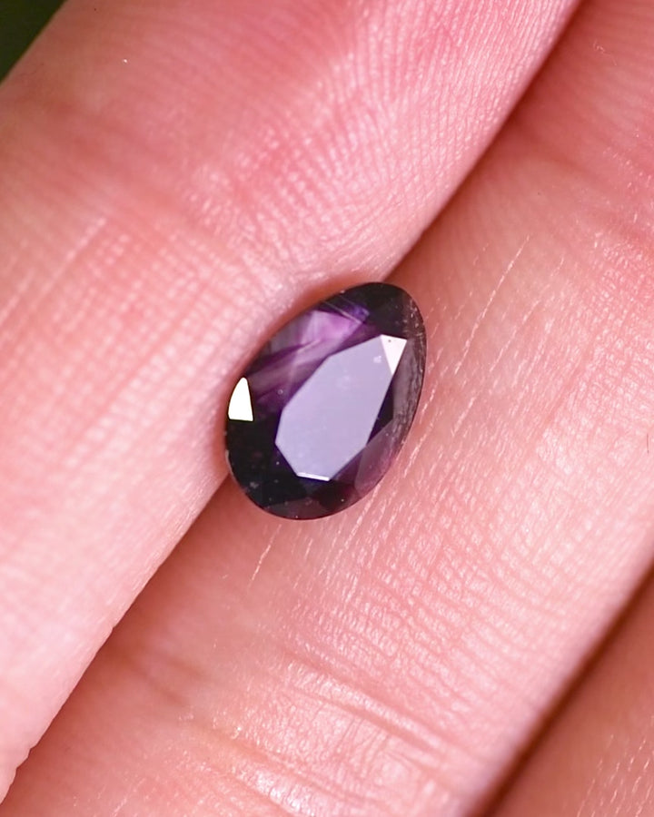 Macro video of 1.98 carat plum and purple sapphire turning slowly, showing internal brilliance, natural inclusions, and craftsmanship of its modified tear drop cut, untreated gemstone from Umba River, Tanzania.