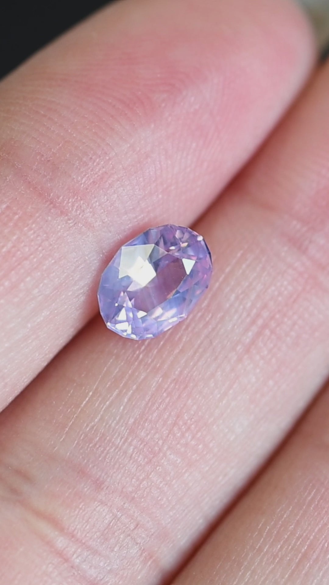 Rotating loose purplish pink sapphire from Ratnapura showing shifting lavender and blush tones across the precision oval mix cut facets.