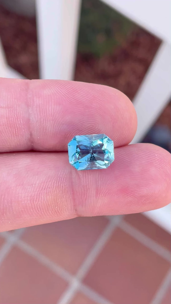 Video display of a radiant 4.63-carat aquamarine gemstone with a double blue hue, expertly cut in an octagon shape. The video emphasizes the gem's transparency and brilliance as it rotates, illustrating its natural, untreated state and Nigerian origin.