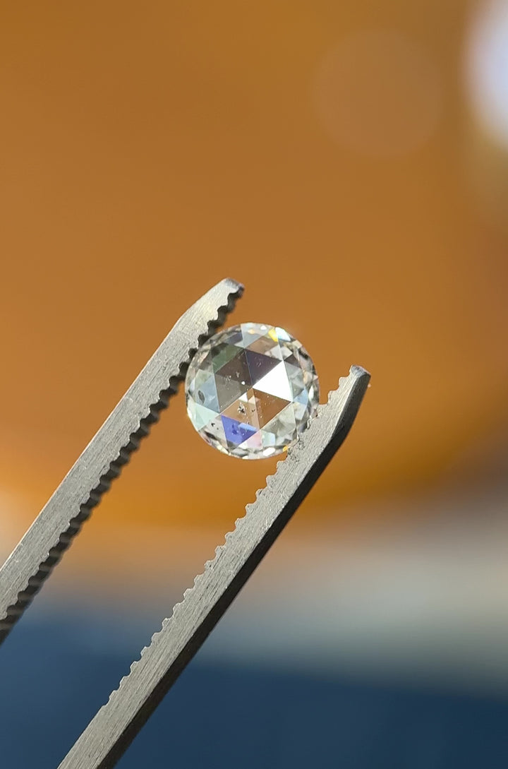 Macro video of 1.04 carat diamond from Gahcho Kué Mine, Canada, rotating in tweezers under natural light to reveal the brilliance and facet pattern of its round rose cut with F color and I1 clarity.