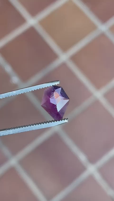 Video displaying the exquisite facets and deep mulberry purple hue of a 2.38-carat custom shield rose cut sapphire from Tanzania, rotating to show its clarity and unique shape.