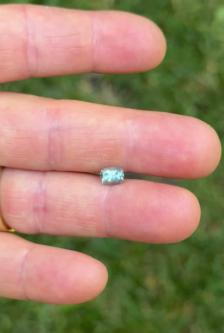 Rotating hand video of 1.15 carat untreated Montana sapphire in custom elongated cushion cut, showing teal and blue-green sparkle in natural light