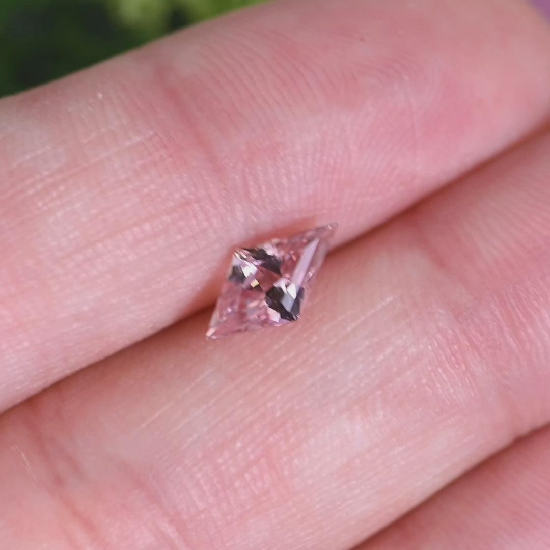 Rotating loose salmon peach pink sapphire from Sakaraha, Madagascar showing the brilliance and soft color shift of the kite mix cut.