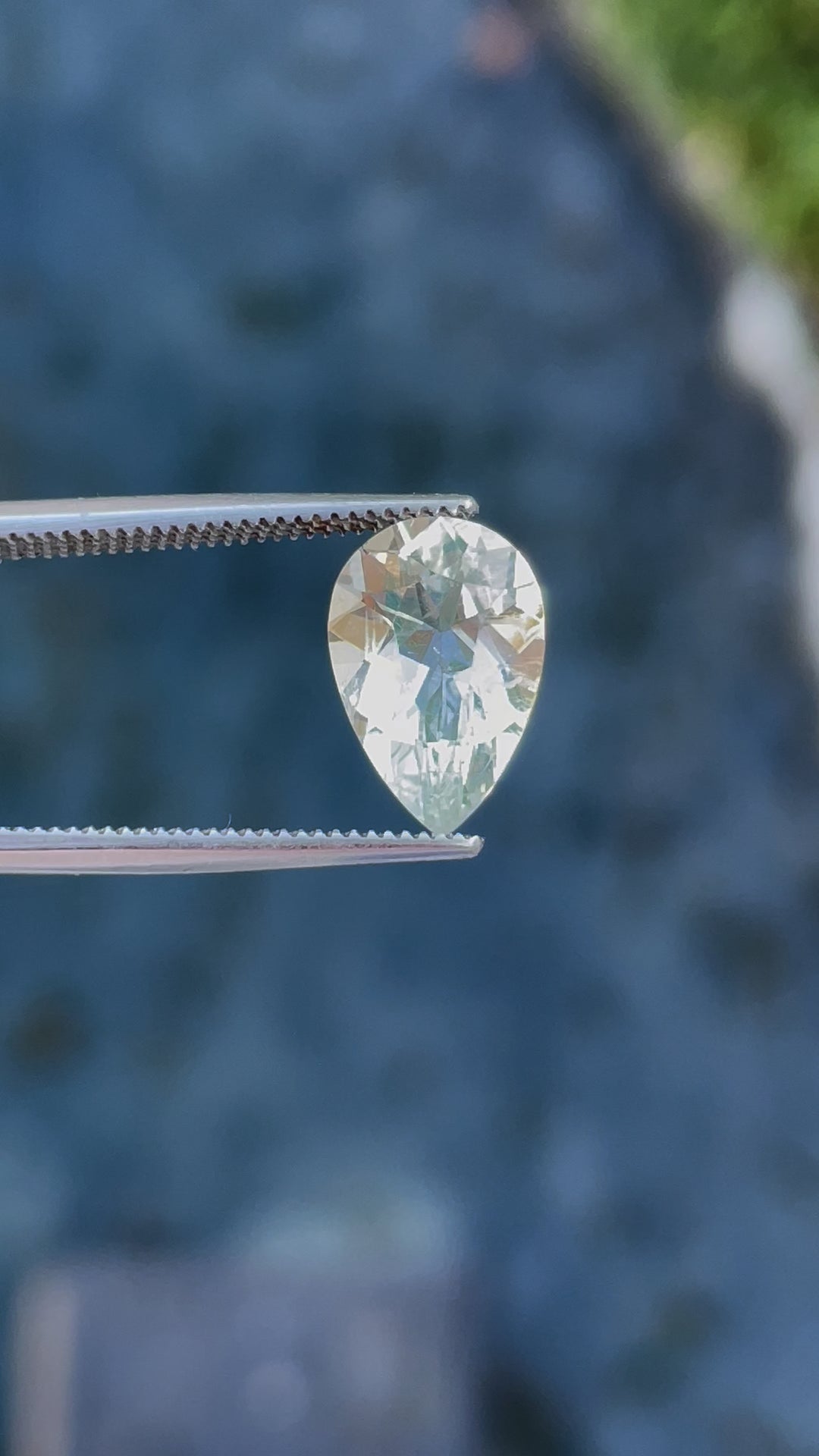 Rotating view of a pear-shaped hyalite opal, capturing the play of light and its vibrant glow under different lighting conditions.
