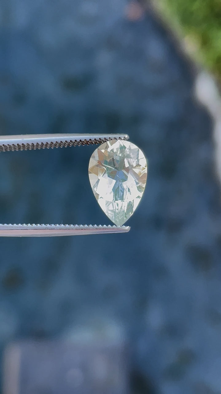 Rotating view of a pear-shaped hyalite opal, capturing the play of light and its vibrant glow under different lighting conditions.
