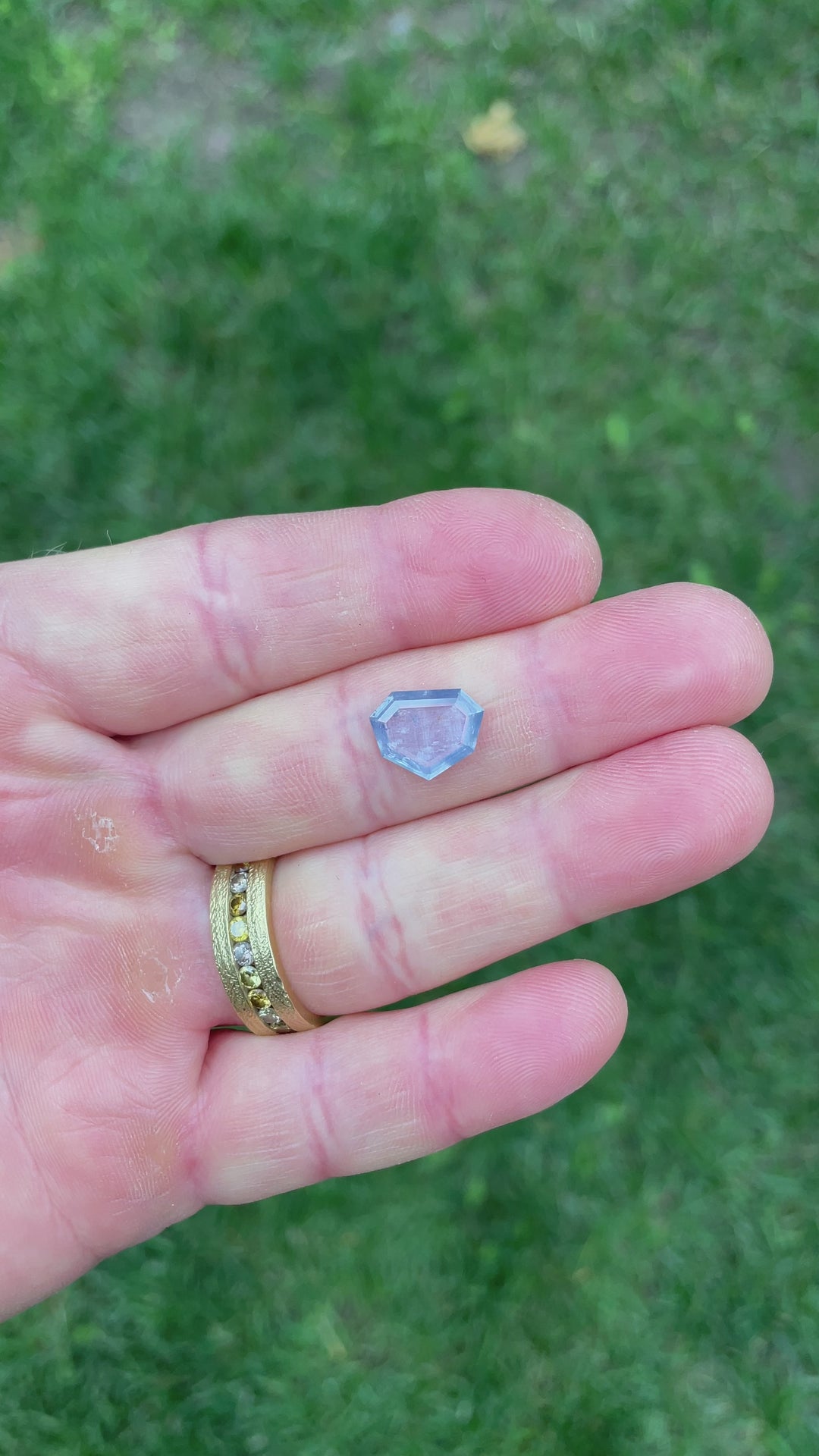Close-up video of a 3.29ct shield cut sapphire, capturing the stone’s delicate blue, teal, and seafoam reflections with clean portrait-style faceting.