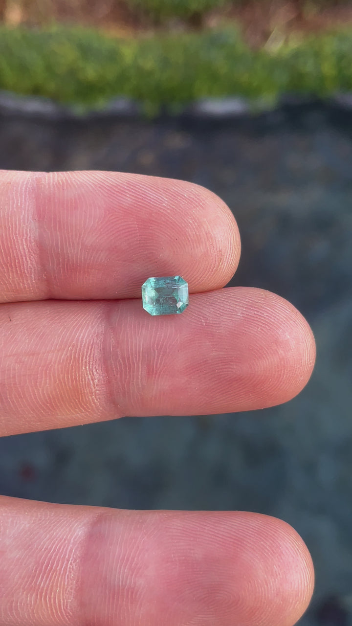 Up-close rotating video of a 1.17-carat green-blue emerald gemstone highlighting its clarity and natural brilliance.