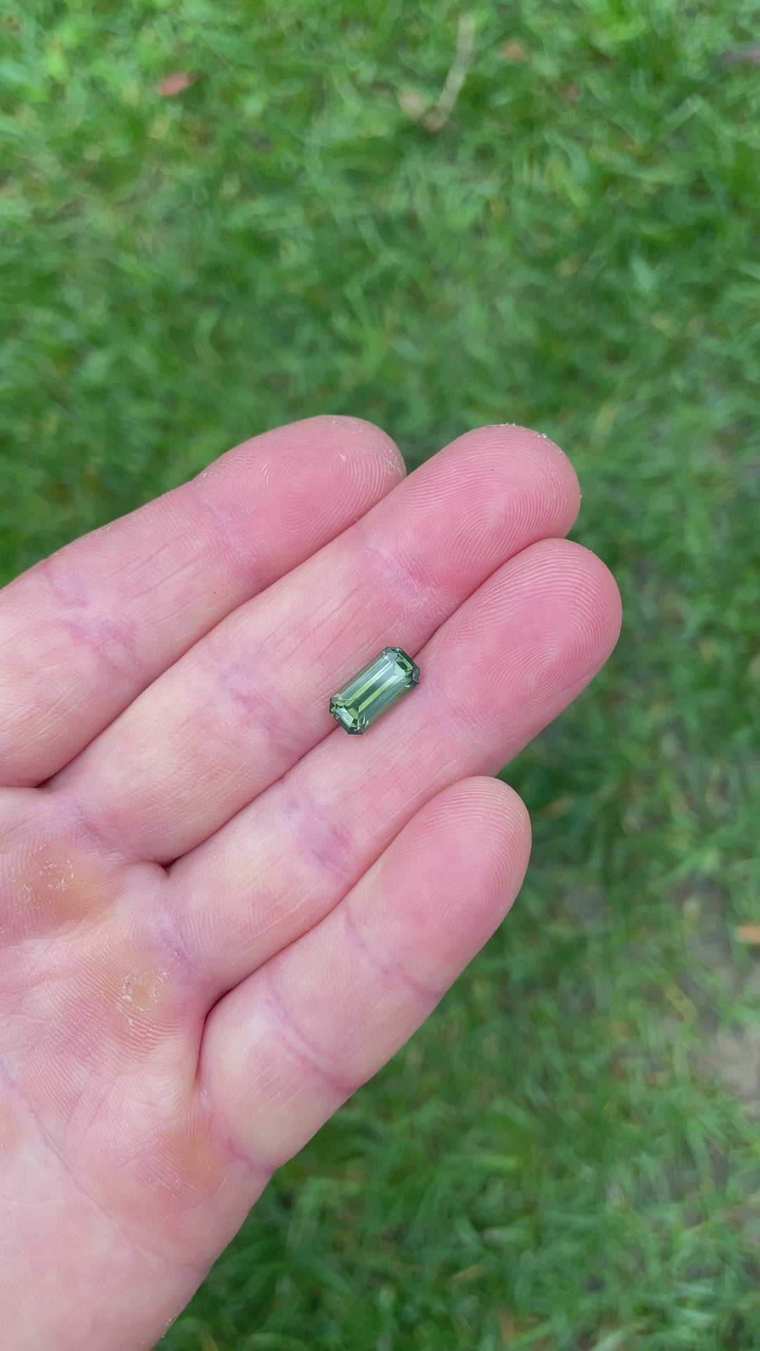 360-degree view of a 3.36-carat Nigerian sapphire with a precision emerald cut, capturing its olive green opalescence and internal glow in motion.