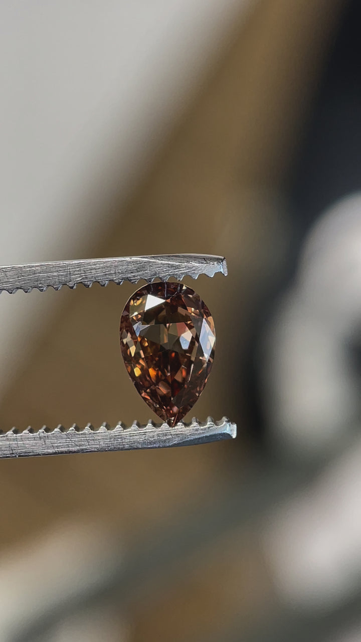 Rotating view of a 1.01-carat Fancy Dark Orangy Brown diamond, showcasing its pear modified brilliant cut and intense brilliance.