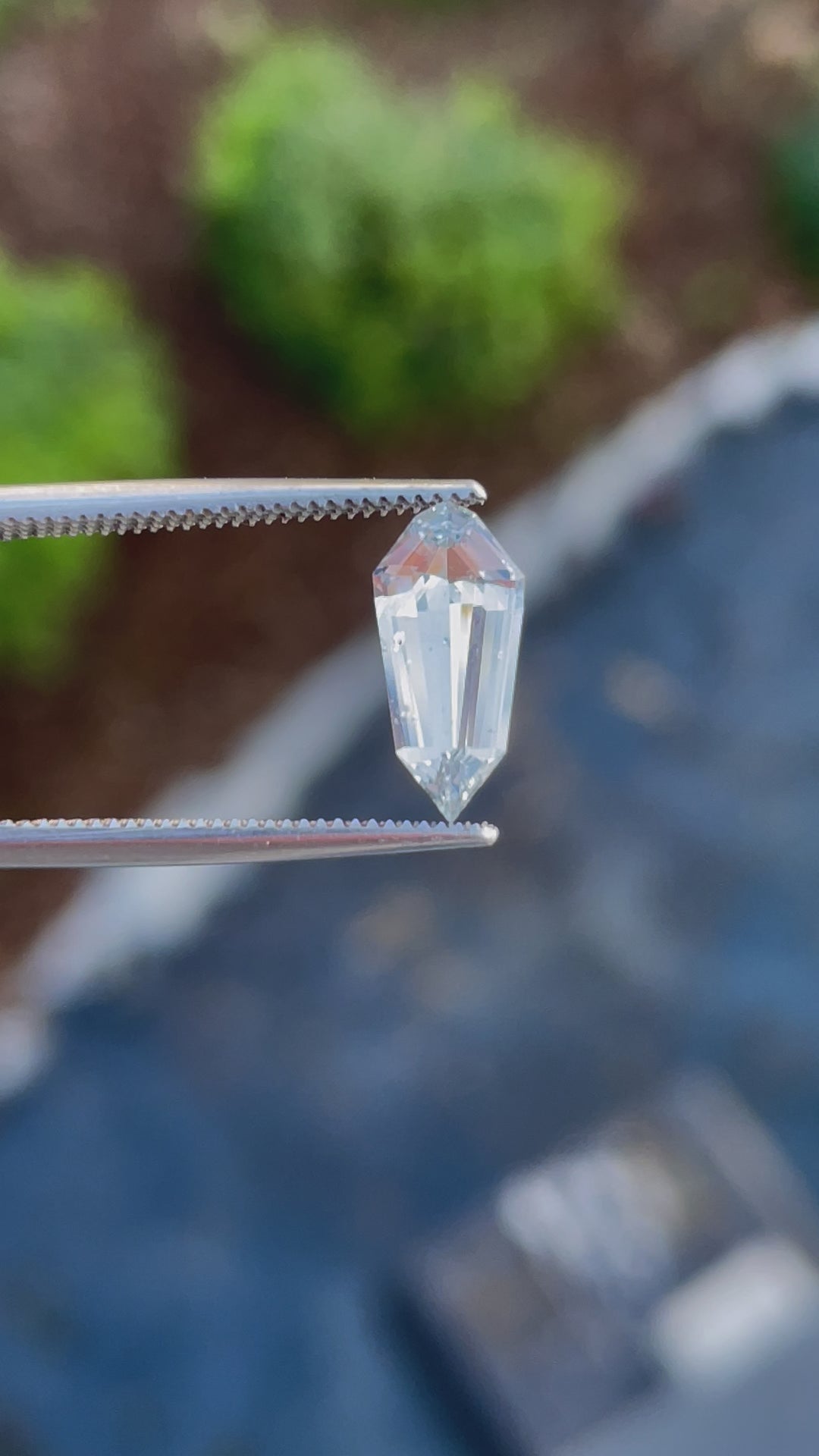 A rotating view of a 1.90-carat custom step cut shield sapphire, highlighting its seafoam hue and faceted details under natural light.
