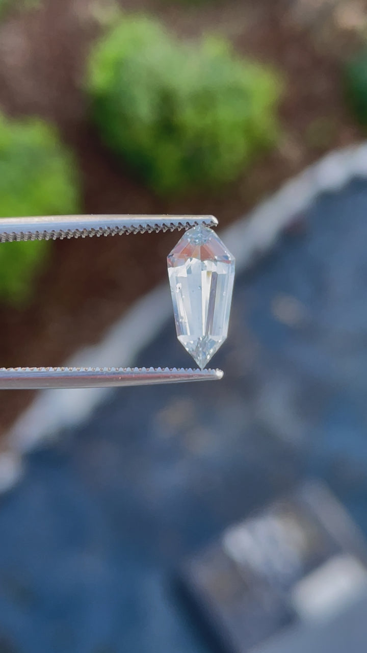 A rotating view of a 1.90-carat custom step cut shield sapphire, highlighting its seafoam hue and faceted details under natural light.
