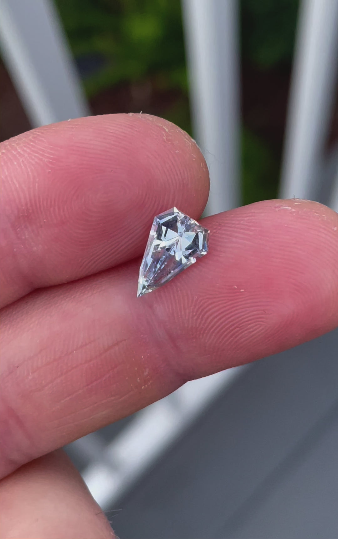 A detailed examination of a shield-cut sapphire, weighing 1.50 carats, displaying its mixed gray, blue, and yellow colors under shifting light conditions.