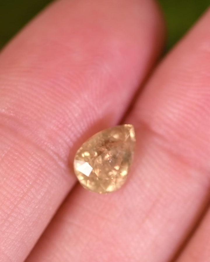 Macro video of 1.90 carat green yellow sapphire turning slowly, capturing reflections and fire within its pear cut facets, untreated gemstone from Umba River Valley, Tanga, Tanzania.