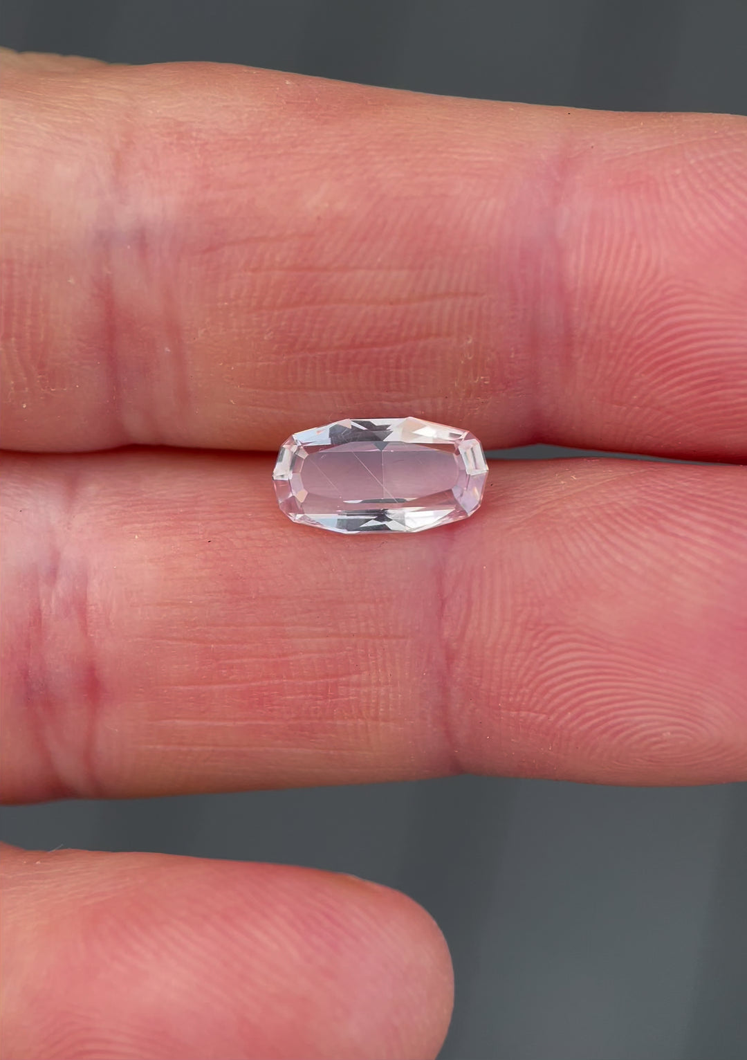 A video demonstrating the brilliance and pastel peach hues of a 2.03-carat sapphire as it catches light in a custom elongated step-cut portrait.