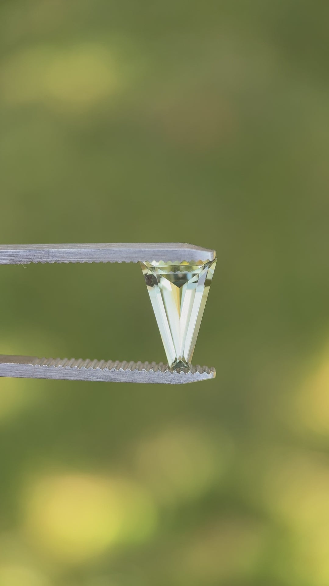 Rotating video of natural 2.02 carat mint green tourmaline under daylight, revealing brilliance through custom tapered baguette step cut facets, untreated gem mined in Congo, Africa.