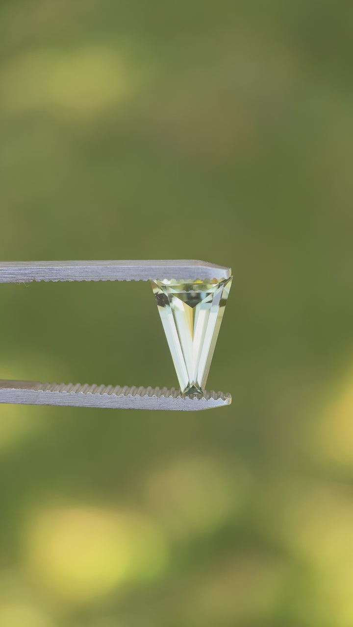 Rotating video of natural 2.02 carat mint green tourmaline under daylight, revealing brilliance through custom tapered baguette step cut facets, untreated gem mined in Congo, Africa.