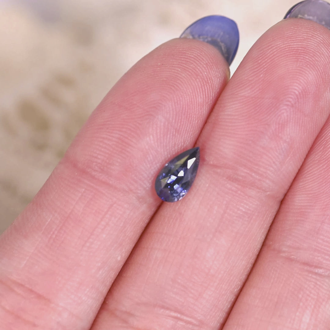 Loose denim blue sapphire from Madagascar rotating in light displaying the brilliance and color of the mixed brilliant pear cut.