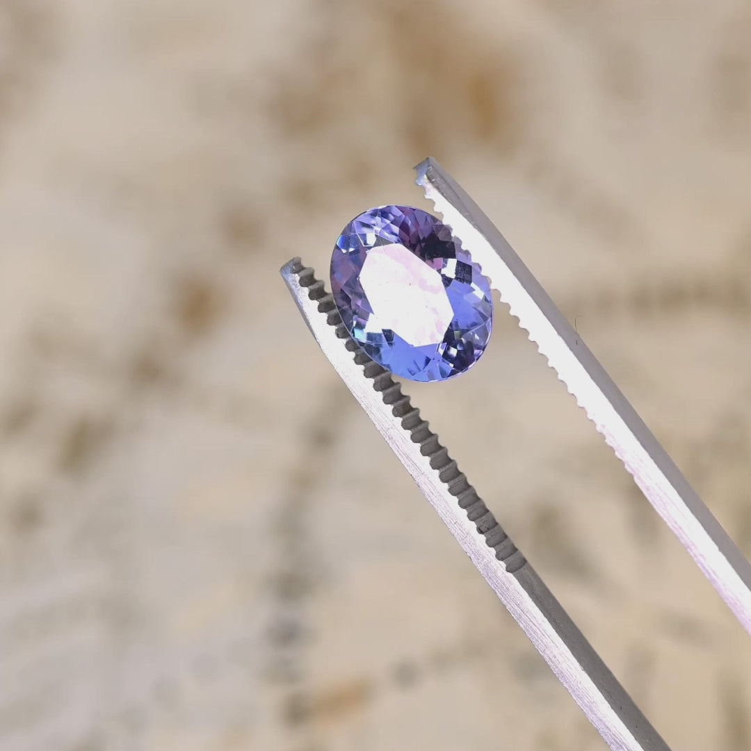 2.50 carat custom mix brilliant oval Tanzanite rotating under light showing powder blue lavender violet color shift and strong brilliance from Merelani Hills