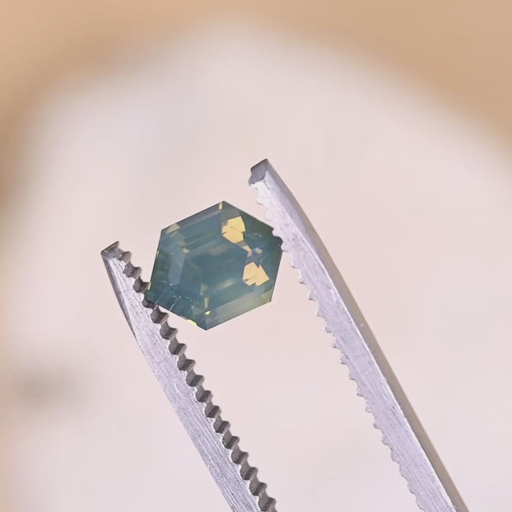 Rotating loose opalescent green yellow sapphire from Sakaraha Madagascar showing the step cut hexagon facets and soft shifting color in light.
