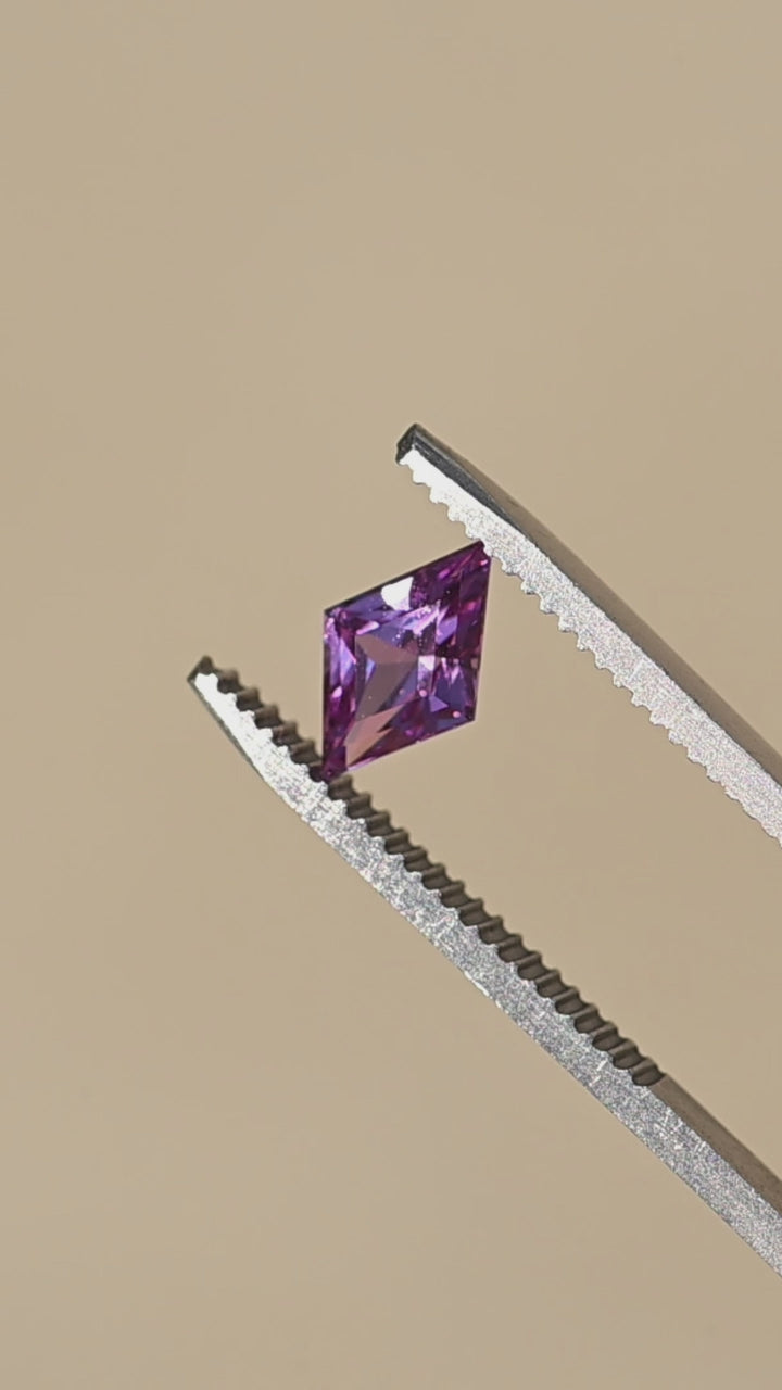 1.15ct hot pink custom kite rhombus cut sapphire sparkling in gem tweezers in direct sunlight.
