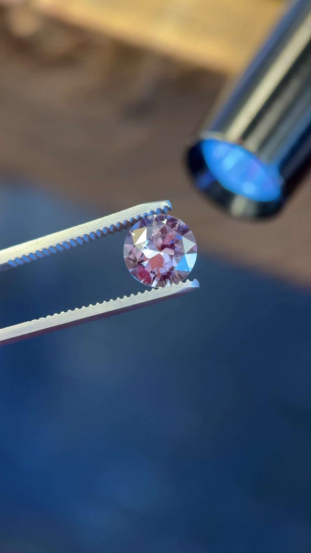 Video of a 2.60CT color-changing sapphire rotating in tweezers, transitioning between grey and steely violet hues in an antique transitional round cut.
