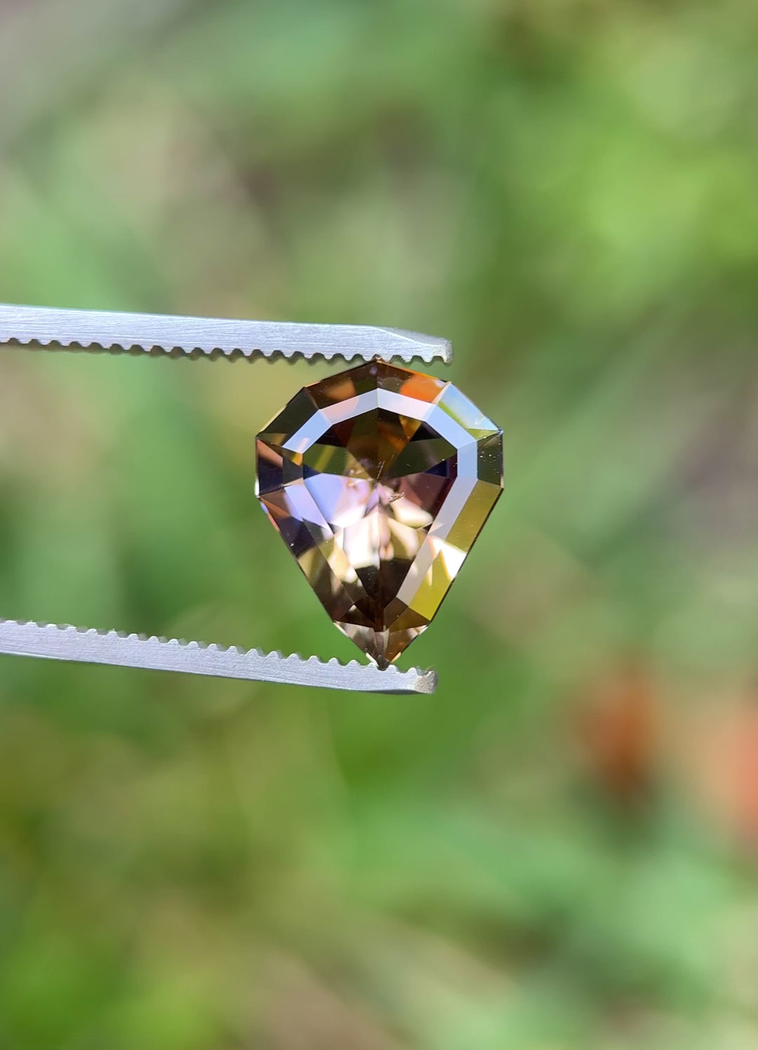 Rotating video of 3.74 carat shield cut Tanzanite held in tweezers, displaying vivid peach, orange, and purple flashes
