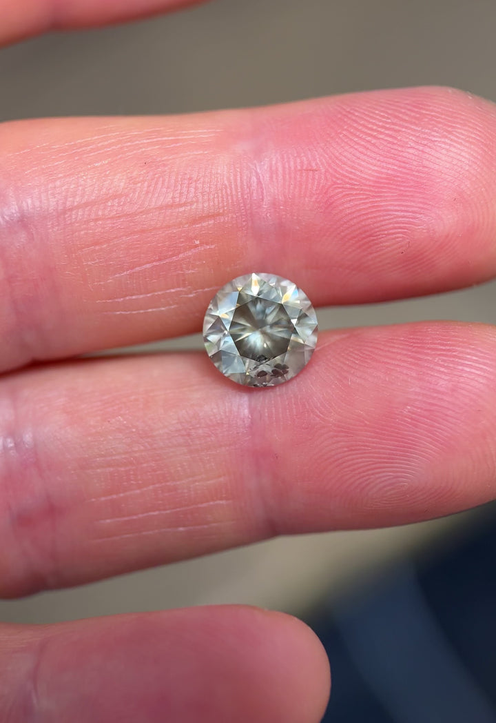 Close-up video of natural 3.99CT Fancy Dark Gray diamond from South Africa, round brilliant cut, turning to display sparkle, color depth, and clarity inclusions under daylight