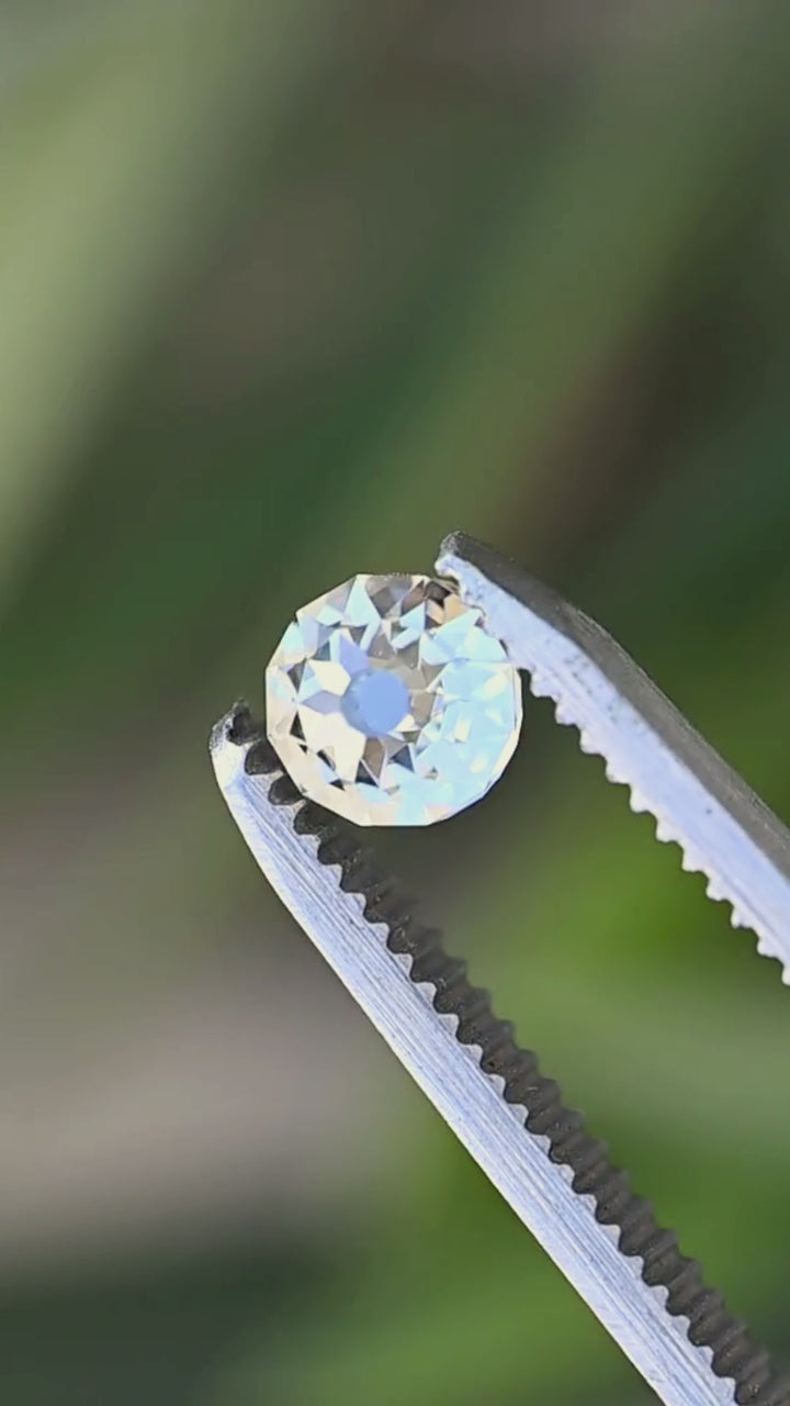 Round Mughal cut South African diamond rotated between jeweler’s tweezers, showing its dimensional profile and changing mosaic of reflections across the facets.