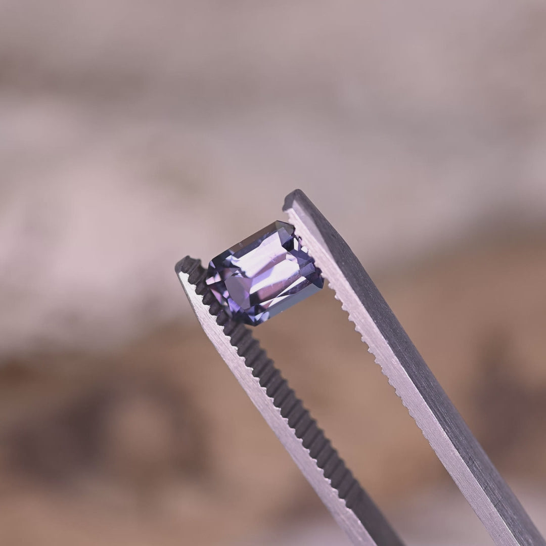 Loose mermaid tanzanite turning in tweezers, revealing purple to blue and green color transitions and step-style radiant faceting from Tanzania.