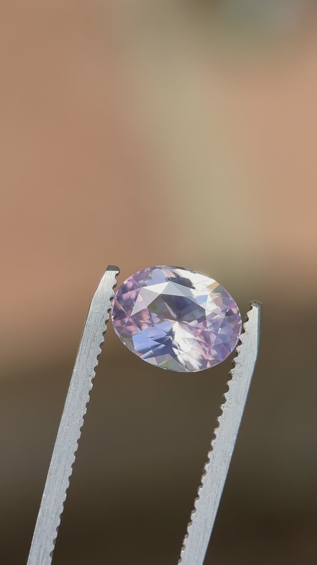 Macro video showcasing the sparkle and internal glow of a 2.52ct unheated opalescent pink sapphire in an oval mix cut, filmed in daylight to capture its ethereal pink tones.
