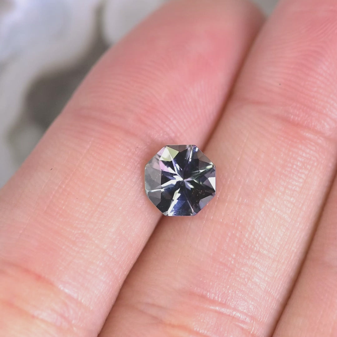 1.49 carat teal green lavender purple Tanzanite octagon rotating under natural light, custom mix brilliant faceted gemstone from Merelani Hills Tanzania showing color shift and sparkle for custom jewelry