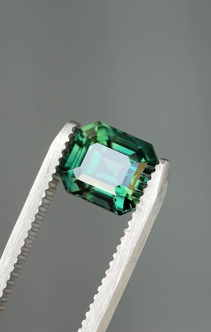 Rotating loose vivid blue green sapphire from Diego Madagascar showing the depth and color shift of the emerald cut as it moves in light.
