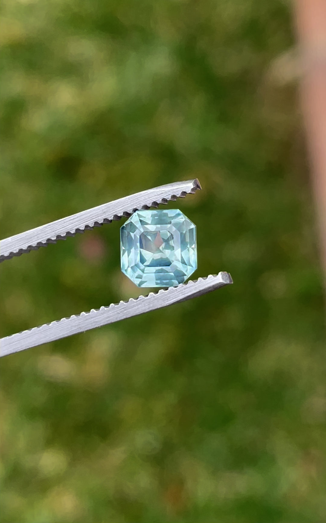 A close-up video of a 1.59-carat opalescent powder teal sapphire resting on a white coral structure, showcasing its unique sparkle and precision cut.