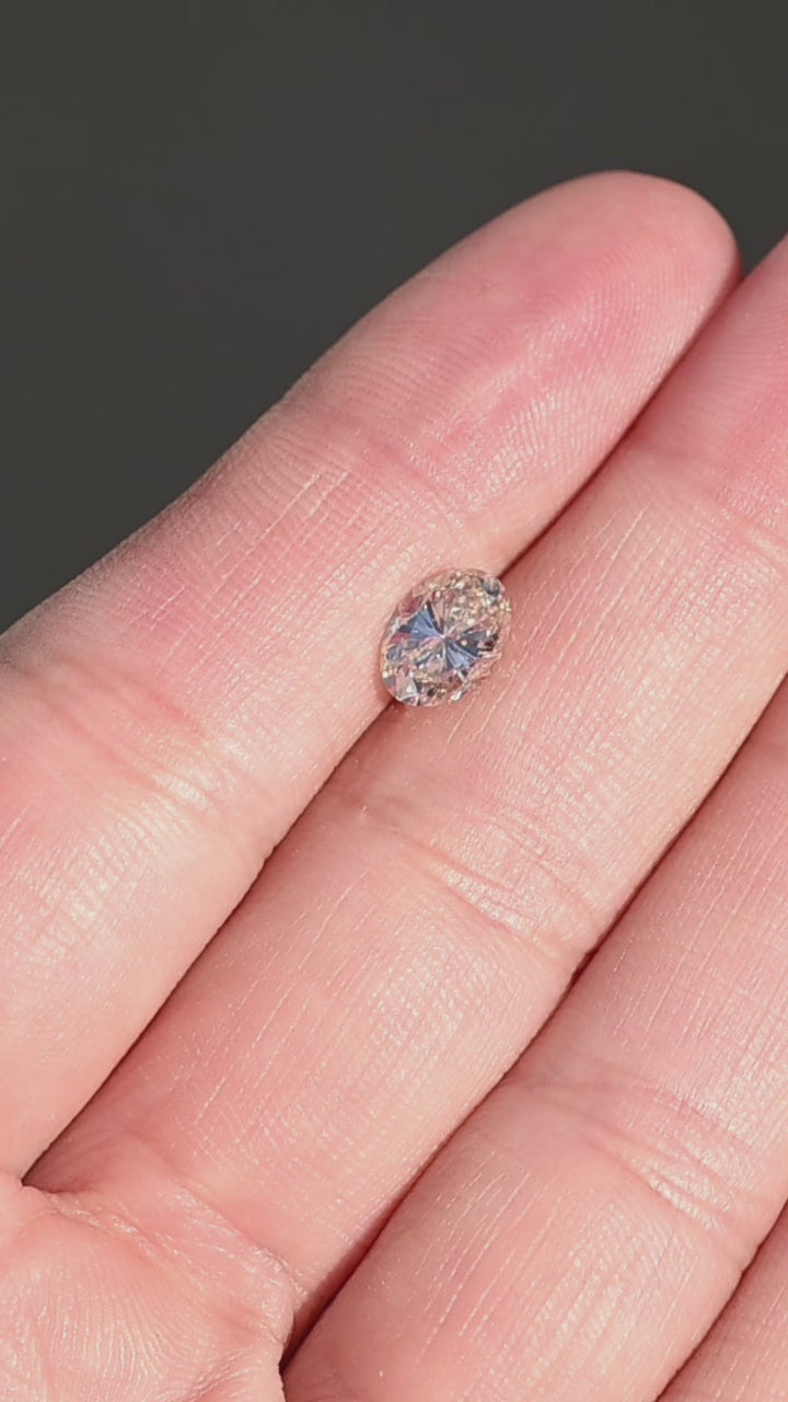 1.23ct champagne oval brilliant cut diamond from Canada rotating on fingertips under direct sunlight. 