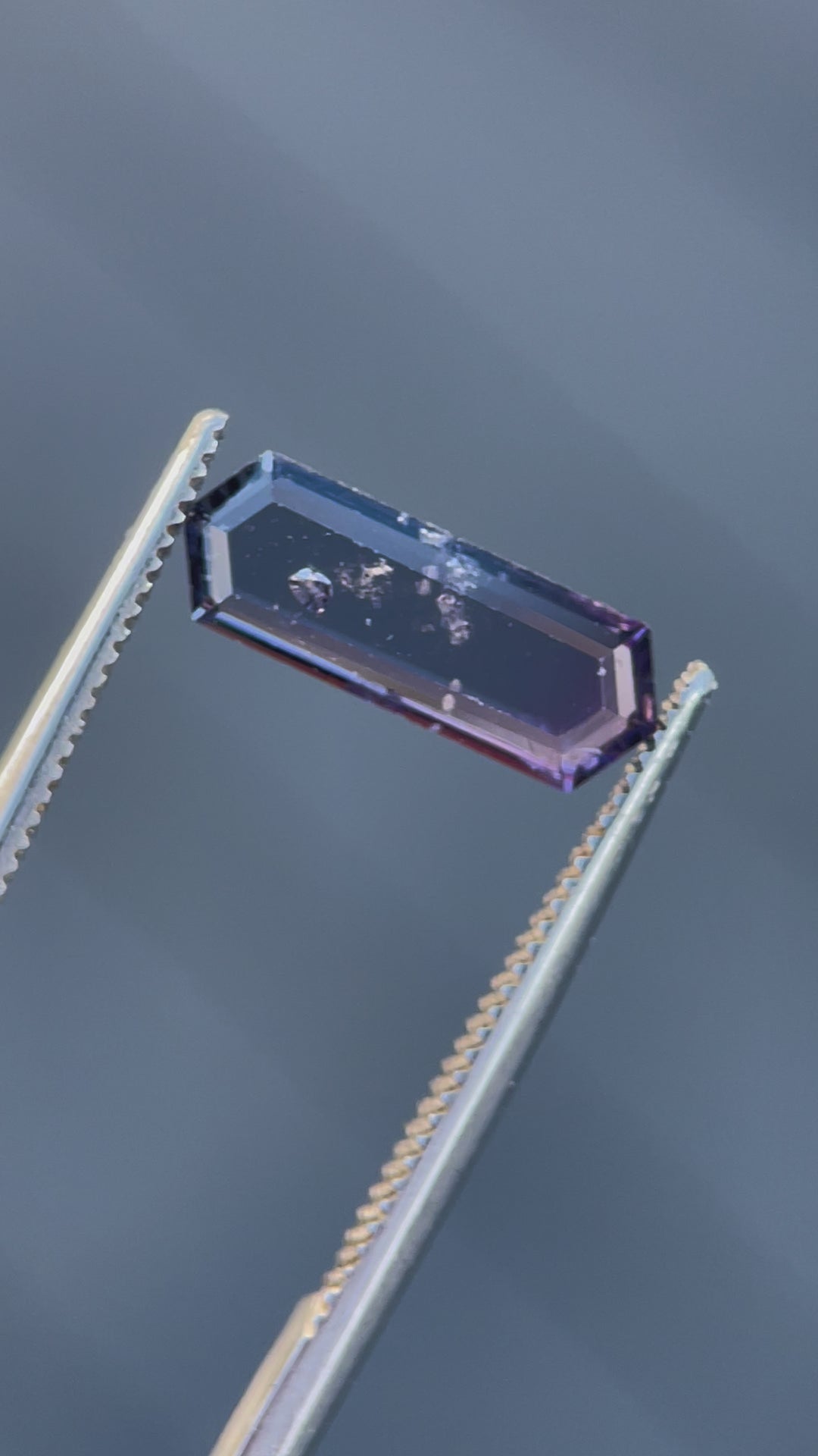 A close-up video of a transparent hexagonal step cut spinel gemstone, highlighting its unique clarity and vibrant hues.