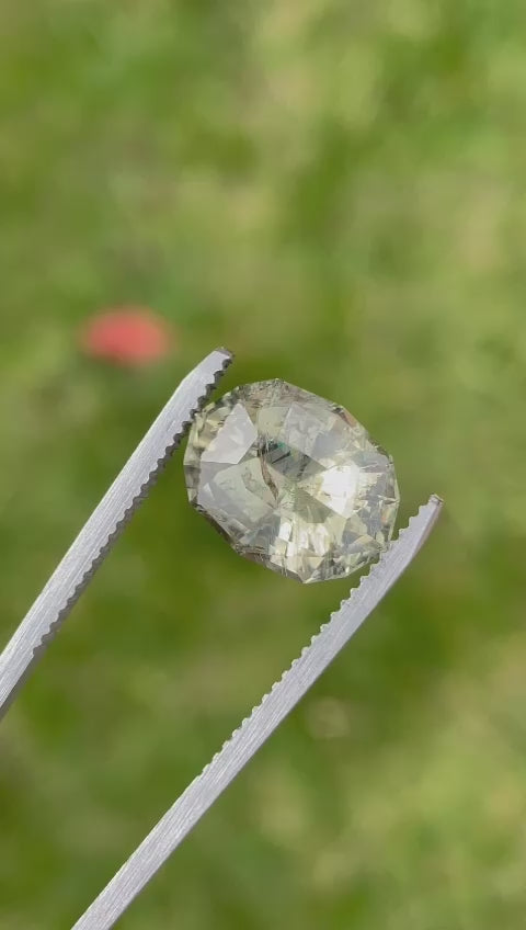 Video displaying the unique color-changing feature of a natural sapphire, transitioning from teal blue green to greenish peach, showcased in various lighting conditions to highlight its vibrant hues and custom geometric oval cut.