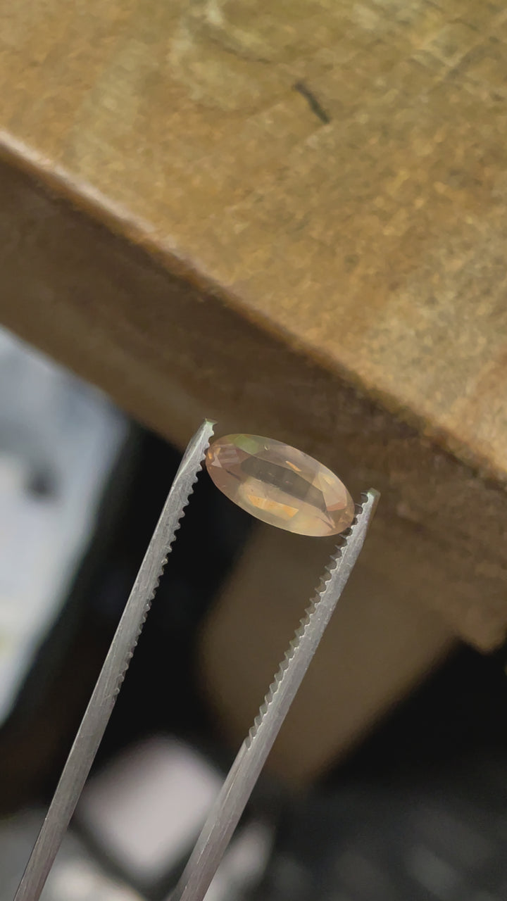 Video capturing the light interaction with a peach opalescent sapphire, demonstrating its clarity and the unique reflections of its custom elongated oval cut.