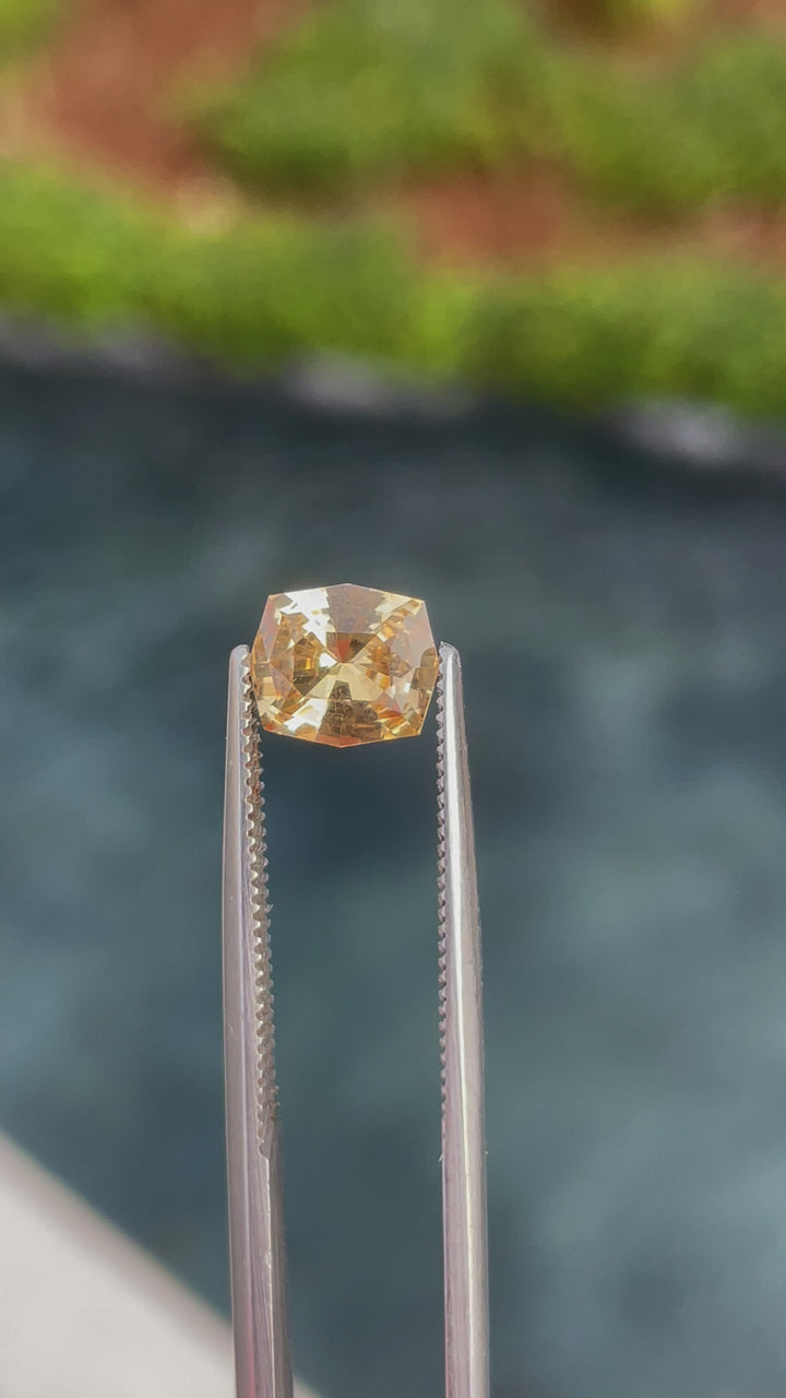 A detailed video showcasing a custom cushion cut sapphire with peach, apricot, and orange tones. The 1.52-carat gemstone from Sri Lanka is untreated, and its unique cushion cut captures light beautifully, highlighting its vibrant colors from different angles.