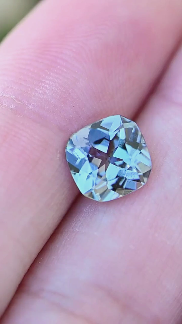 A 2.08 carat untreated Tanzanite rotating on fingertips in natural light, revealing remarkable pleochroic shifts between teal, blue, green, and purple with every movement.