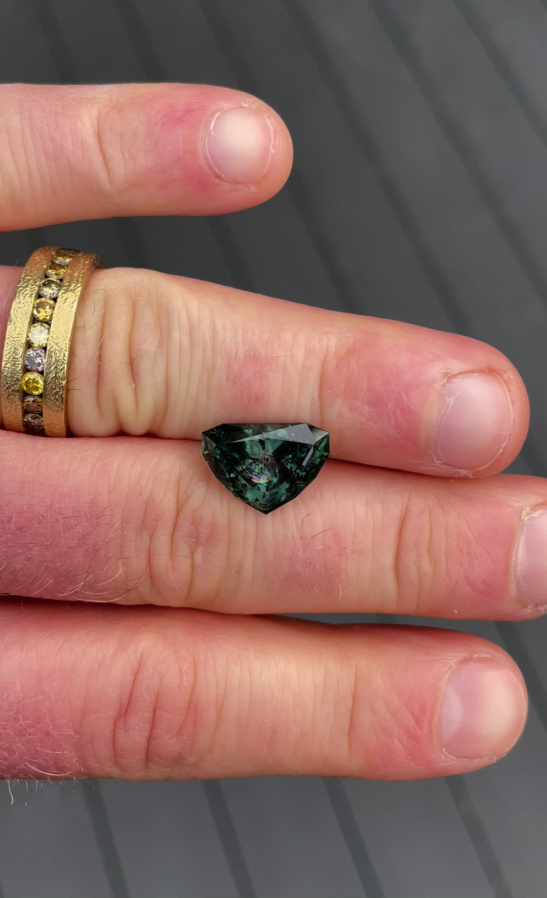 7.06-carat sapphire in a modified shield brilliant cut, showcasing its bluish-green hue transitioning to gray-purple, sourced from Montana with no treatment.