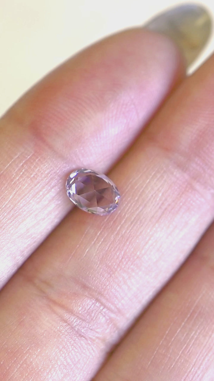 1.19ct lavender purple pink sapphire rotating in hand, revealing bright pastel flashes and precision oval cut brilliance.