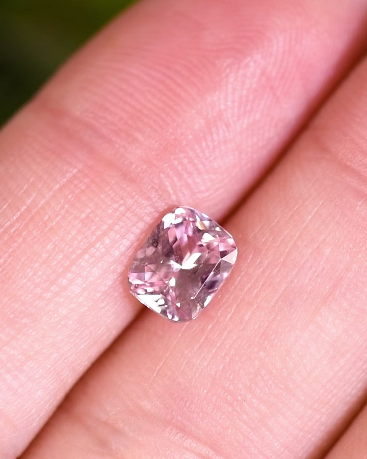 Close-up video of 1.57 carat pink peach sapphire resting on fingertips, showcasing the gem’s natural sparkle, cushion cut symmetry, and untreated origin from Sakaraha, Madagascar.