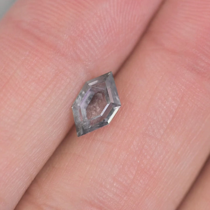 Close-up rotating video of 1.03 carat blue purple gray Montana sapphire, custom hexagon portrait tablet cut displaying light reflection and natural Montana origin.
