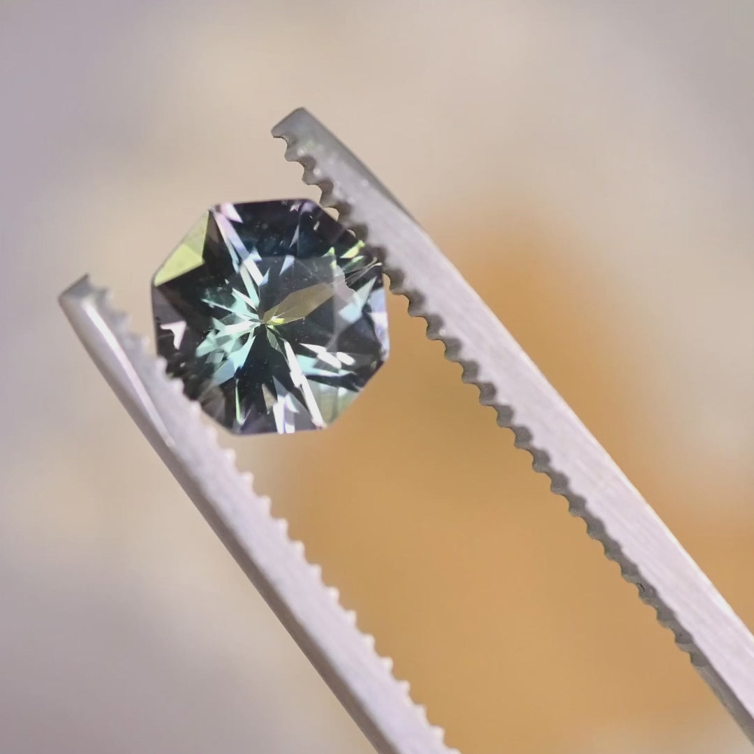 Close-up video of 2.45ct gray blue Tanzanite oval held in tweezers, untreated precision faceted gemstone from Tanzania displaying sparkle, clarity and natural lavender blue tones