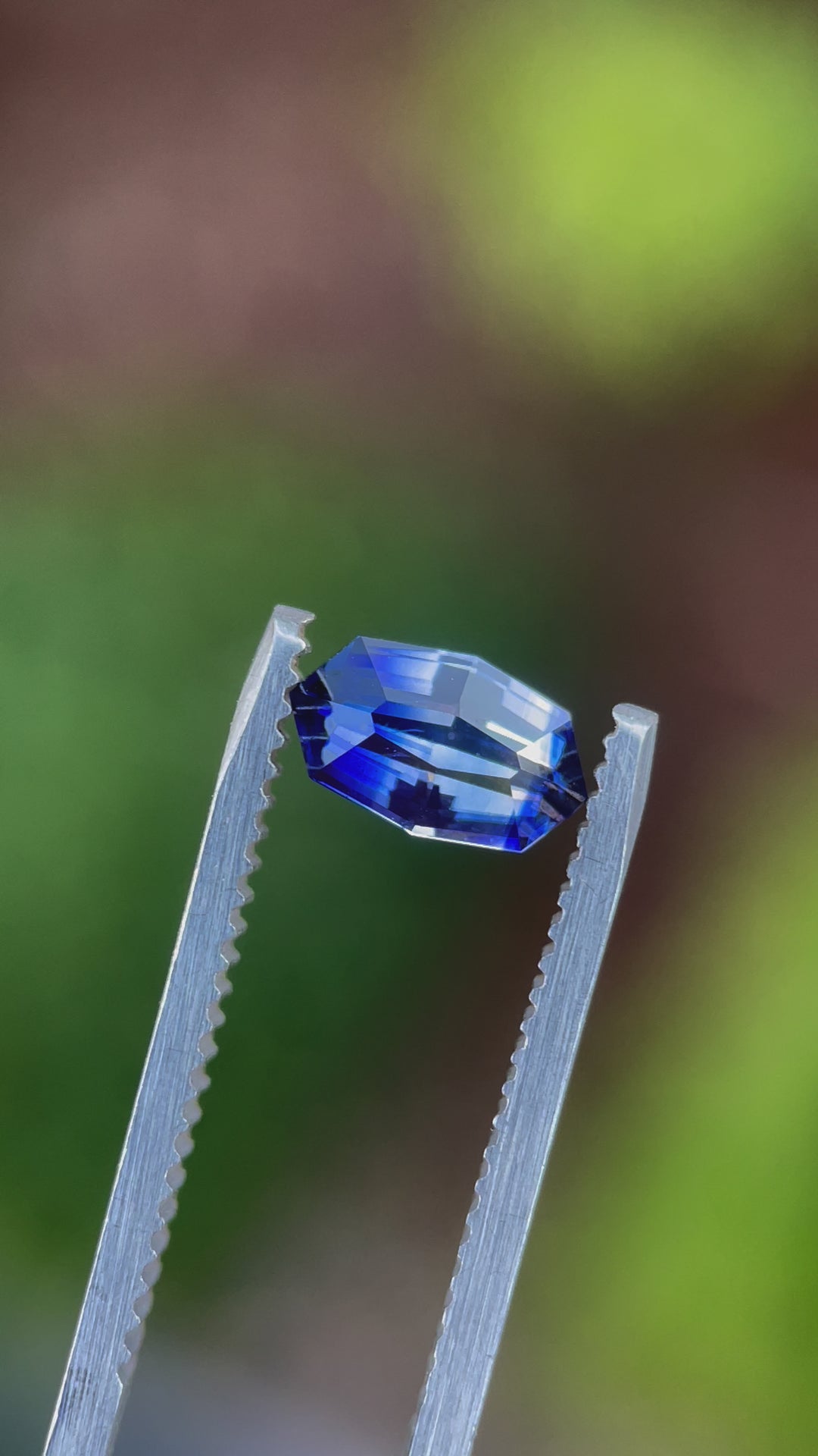 Video detail of a 1.03 carat bi-color sapphire held in tweezers, focusing on its custom geometric marquise shape and the stone’s polished facets, revealing the precision of its Sri Lankan craftsmanship and heated treatment.