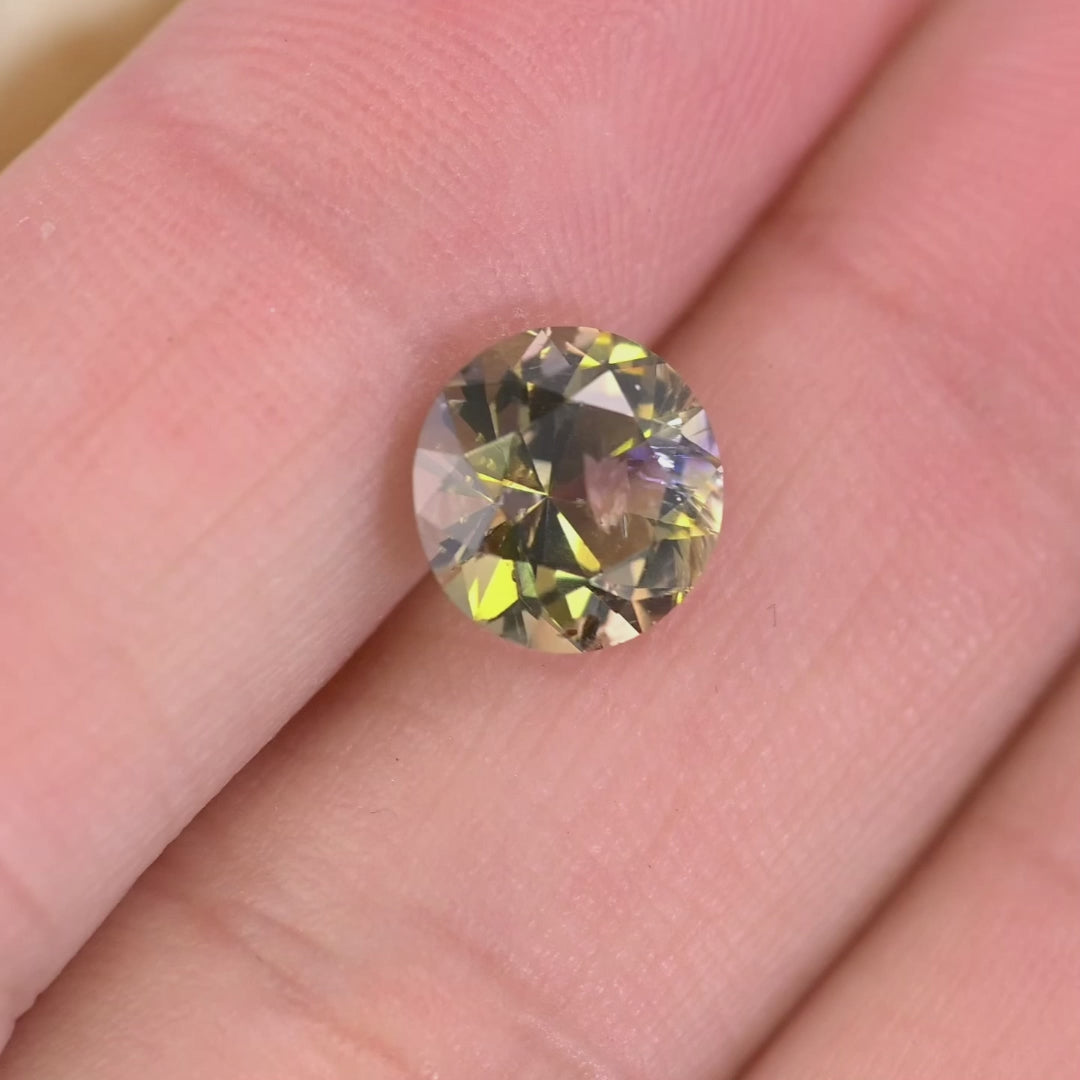 Video of a 2.33ct untreated Tanzanite rotating under light, revealing teal, green, purple, and golden yellow color play in an antique style round transitional brilliant cut from Tanzania