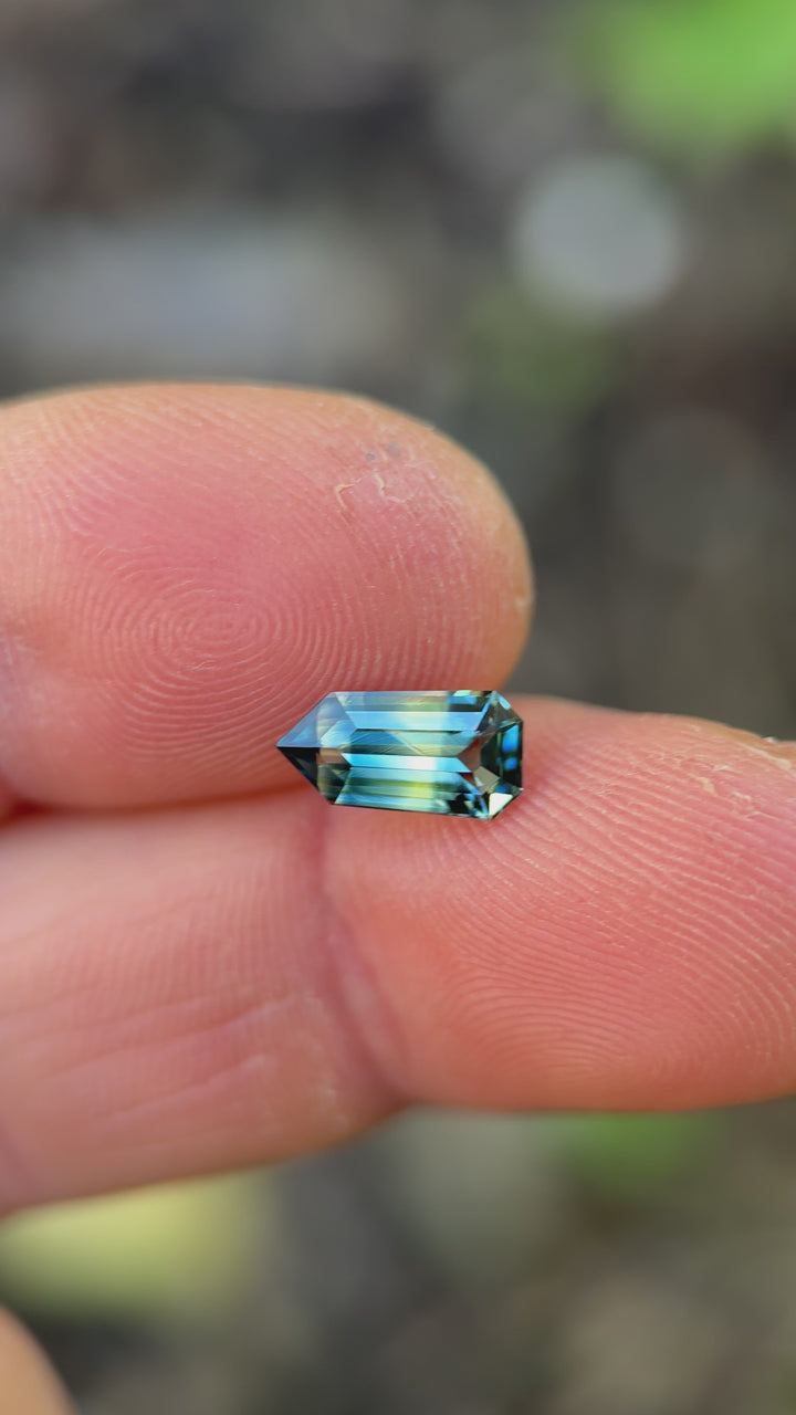 Rotating loose yellow blue green parti sapphire from Diego Madagascar showing the brilliance and shifting color zones of the custom modified step cut shield.